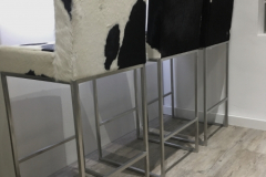 black and white cowhide stools with backs and steel frames.