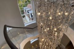 Stunning staircase and chandelier further enhanced by black and gold embossed leather handrail.