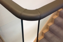 Flat handrail on glass, covered in leather.